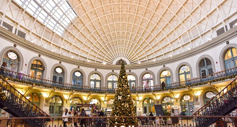 A photograph of Leeds Corn Exchange decorated in Garlands and Lights with a giant Christmas Tree in the middle decorated by Fizzco.l