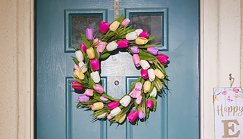 a blue front door with a bring and colourful spring wreath hung in the centre.