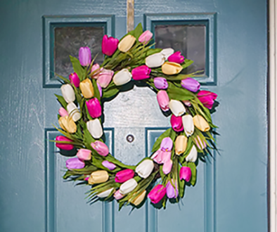 a blue front door with a bring and colourful spring wreath hung in the centre.