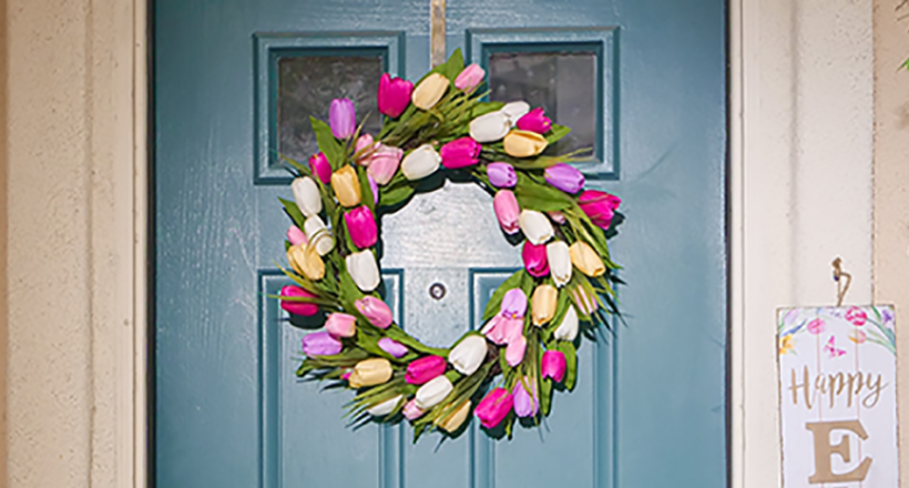 pexels-kindel-media-7102202 a blue front door with a bring and colourful spring wreath hung in the centre.