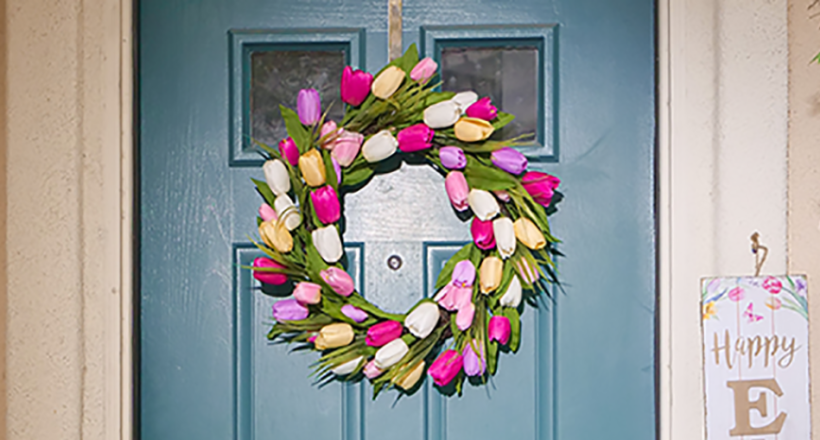 a blue front door with a bring and colourful spring wreath hung in the centre.