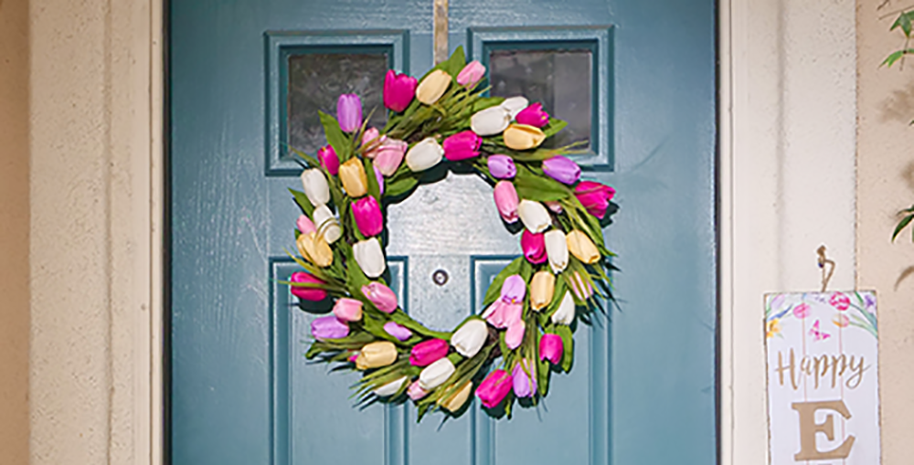 a blue front door with a bring and colourful spring wreath hung in the centre.